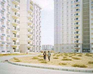 Two workers stand on an arid piece of land amongst towerblocks in the new town of Kilamba, south of Luanda, the capital. Kilamba has been built by a Chinese company in three years and is supposed to b...
