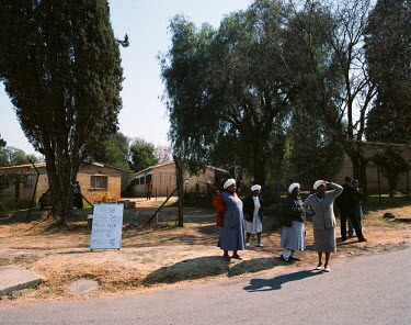 After Sunday mass in a local church in Soweto, a group of women stand next to a sign advertising fresh eggs for sale by the side of the road.