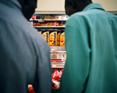 Two men inspect products in a deep freezer at a local Shoprite supermarket in Soweto on pay day. A few days earlier the aisles had been empty but on payday people stock up on essentials in large numbe...