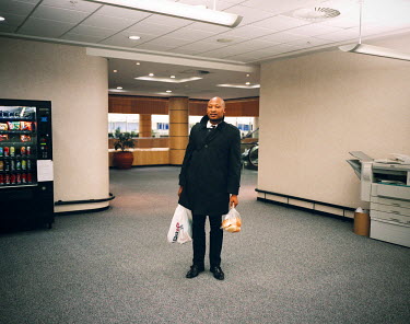 An employee of an insurance company poses with the shopping he has done during his lunch hour in the foyer of his office block in the Central Business District. During the Apartheid years, the Central...