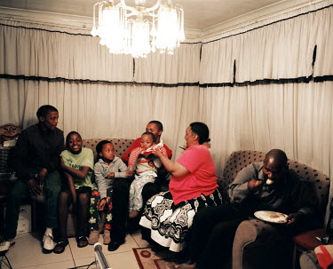 A family gathering in the Vosloorus district of Johannesburg, a poor suburb in the soutwest of the city. The father of the house, on the right, has been served first and is eating ^pap^, a cereal porr...