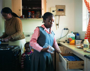 A mother prepares food for her children after her daughter returns from school in the black middle class suburb of Cresta. Her husband, a Zimbabwean, is employed in an IT company.