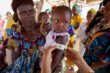 A baby has a malnutrition test using a mid-upper arm circumference (MUAC) measurement. Each month Community Health Leaders, trained by Oxfam, work in villages to do a survey of malnutrition levels, gi...