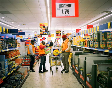 Nigerian migrants Happy, Ibrahim and Henry shopping at the Lidl supermarket in Breno. A person from the K-pax association (a refugee's social welfare organisation) is following them and pays for their...