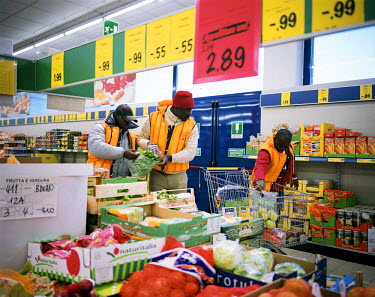 Nigerian migrants Happy, Ibrahim and Henry shopping at the Lidl supermarket in Breno. A person from the K-pax association (a refugee's social welfare organisation) is following them and pays for their...