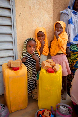 Young girls stands beside water containers with soap, distributed by Oxfam to help with sanitation and hygiene at the Azel Treatment Centre, a small community health centre, largely dealing with malnu...