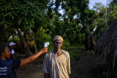 A World Health Organisation (WHO) worker checks the temperature of a man who has been in contact recently with an Ebola victim in the village of Tana. In this region the WHO has decided to allow peopl...