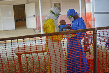 Two MSF (Doctors Without Borders) health worker hold in their arms Mibemba Soumah who is infected with Ebola at the MSF Ebola treatment center in Conakry. Though the spead of infections has been reduc...