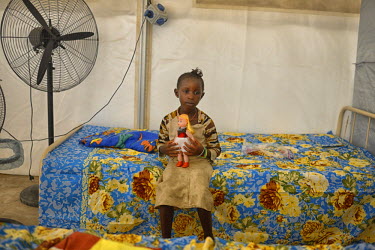 A young girl from the Soumah family sits on a bed in the MSF (Medecins Sans Frontieres, Doctors without Borders) centre in Conakry, the capital. The family is from the village of Tana in the prefectur...