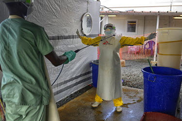 An MSF (Doctors Without Borders) health worker is disinfected with chlorine before leaving the high risk zone at the MSF Ebola treatment center in Conakry. Though the spead of infections has been redu...