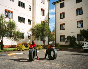 Twoo boys play with car tyres outside a group of apartment buildings in the suburb of Ambakasi, near Nairobi airport.