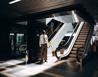 A man stands beside an escalator on the ground floor of the Loita Building, a business centre where many Kenyan and foreign companies have their offices.