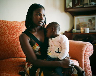 Ericka in her living room with her one year old daughter, Angel. Ericka works for a foreign company and carries out financial analysis for them. She also owns a small beauty product company that she h...