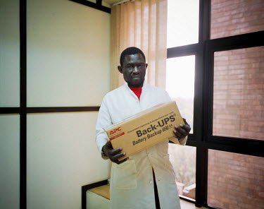 Oussmane carrying boxes as part of his job as a handy man for a foreign research institute. His wage provides him with a middle class salary but doesn't allow him any extras. After 25 years of working...