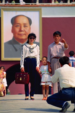 A family with one child pose before giant portrait of Chairman Mao, in Tiananmen Square.