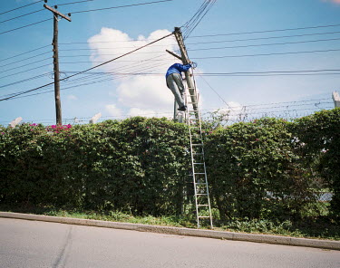 Billal, a phone company technician, mends a telephone pole on the edge of a highway.