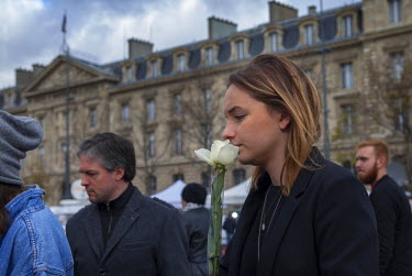 A woman holding flowers at one of the many impromptu memorial sites created by the public at the sites of the atrocities and in the Place de la Republique as Paris struggles to come to terms with the...