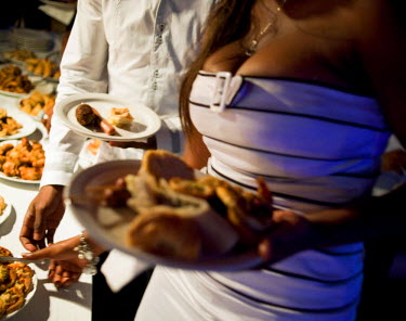A couple getting food from a buffet at an evening event in a bar.