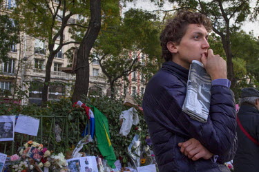 A young man at one of the many impromptu memorial sites created by the public at the sites of the attrocities and in the Place de la Republique as Paris struggles to come to terms with the events of 1...