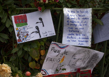 A drawing depicts the attack at the Bataclan, attached to a railing along with notes and flowers, at one of the many impromptu memorial sites created by the public at the sites of the atrocities and i...
