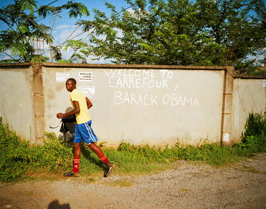 A man runs past a graffiti that reads 'welcome to Carrefour, Barack Obama'. The area is near the stadium and land prices there are increasing as it has become popular with the middle classes seeking t...