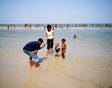 A family at the beach on a Sunday afternoon. In Mozambique, couples have an average of five children. Although among the middle classes the number is reduced (two or three usually) because parents wis...