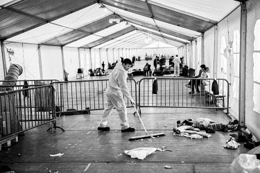 Workers clearing rubbish left behind by one recently departed group of asylum seekers, at a processing and holding centre, before the next group arrive.