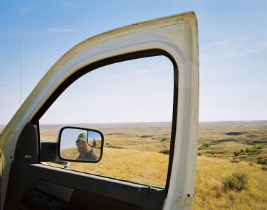 Mike Wilson is seen reflected in the mirror of his pickup truck, looking over his land in North Dakota. At 30, he owns 1,200 hectares of land and 250 cows but most of his income comes from the shale o...