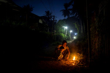 A woman burns trash at dusk in the village where poet and National League for Democracy (NLD) candidate Tin Thit, who beat former Defence Minister and Burmese Army General Wai Lwin from the government...