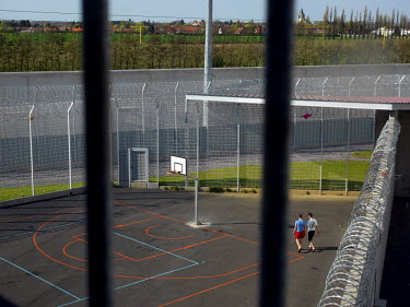 Inmates in an exercise yard at the Detention Centre of the Centre Penitentiaire de Lille-Annoeullin. In the background is the city of Annoeullin.