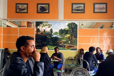 People drinking coffee in Bar Vittorio where the walls are graced by a painting by Emmanuel Chilazghi. (iPhone photo).