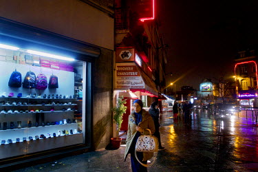 A woman walk past the illuminated shop fronts in Brussels' Molenbeek neighbourhood.