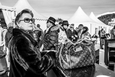 A woman in fur waits to be served a drink during a break in the action at an international Snowpolo tournament.