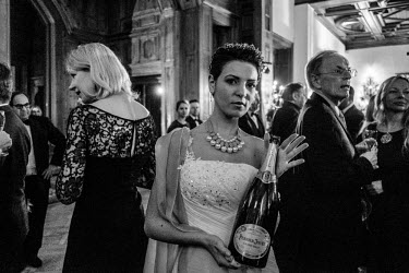 A guest at a reception, held before a fashion show at the Badrutt Hotel, holds a magnum of champagne.