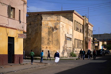 People walking in the street past the Alfa Romeo building. Built in 1938, the Art Deco building was once the African headquarters for the Italian car makers. Asmara is a treasure trove of Art Deco arc...
