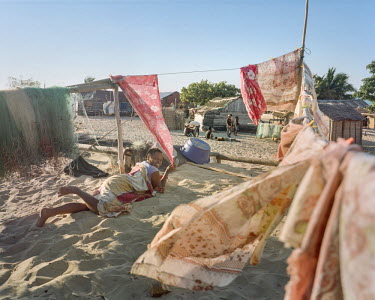 A woman shelters from the sun in a Vezo village, whose culture is strongly linked to the sea.