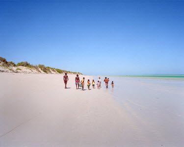 A family walking to the place in the lagoon where they have set up a seaweed farm.