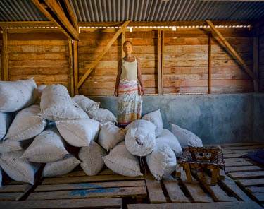 A young woman stands beside sacks of seaweed, that day's production. Every month, 30 tons are packed by the 250 villagers, generating an important additional monthly income.