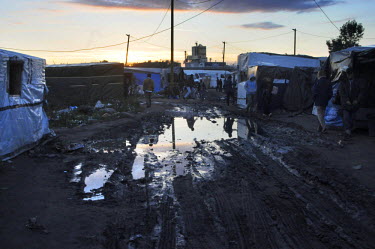 People walkingpast a muddy path that runs through 'The Jungle', an informal settlement where several thousand migrants and asylum seekers are stranded while they try to illegally enter the UK by jumpi...
