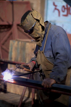 A welder with a makeshift protective mask at the Medeber metalwork market. This huge market is the centre of Asmara's recycling industry.