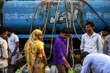 Residents gather at a Delhi Jal Board water supply tanker to collect water in the slums of Govind Puri. The Delhi Jal Board distributes multiple tankers of free water to all residents in the slum area...