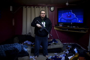 Dennis Davis shows his automatic rifle while standing in his living room. Shishmaref is a barrier island with a population of less than 600 Alaska native Inupiaq people located 30 miles south of the A...