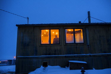 A resident of Shishmaref looking outside through a window of his home.Shishmaref is a barrier island with a population of less than 600 Alaska native Inupiaq people located 30 miles south of the Arcti...