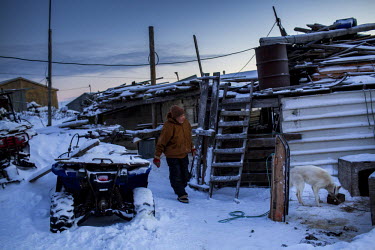 An elderly resident checks his dogs outside his home in Shishmaref, a barrier island with a population of less than 600 Alaska native Inupiaq people located 30 miles south of the Arctic Circle. The is...
