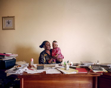 Madame Ndiaye in her office, carrying her second daughter. She manages an employment agency, with a permanent staff of about 10 people. Her first child was born in a public hospital, but the condition...