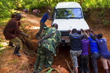 A team from a bank which is transporting funds across the country maneouver one of their vehicles out of a huge pothole in a road as they travel the remote region to pay state employees and civil serv...