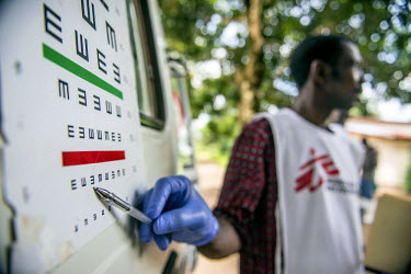 Health promoter Joseph Fofana conducts an eye test during a MSF outreach mission to Kumrabai village. Many survivors of Ebola still suffer from physicial (including problems with vision), social and p...