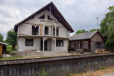A new house, stands beside the old one it is replacing, built by people who left Romania to work in western Europe.
