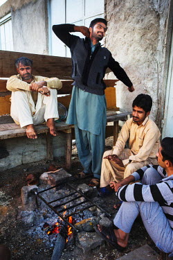Men drink tea by a fire at the start of their working day in the Gouran shipyard constructing a traditional Iranian Lenj boat. This ship is being built by ten Pakistani carpenters who will be paid a t...