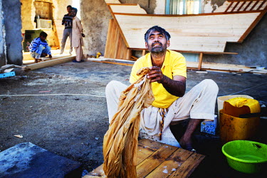 Ghafoor Ahmed washes clothes in the compound where he lives with his co-workers. They are living in the Gouran shipyard while constructing a traditional wooden Iranian Lenj boat. This ship is being bu...